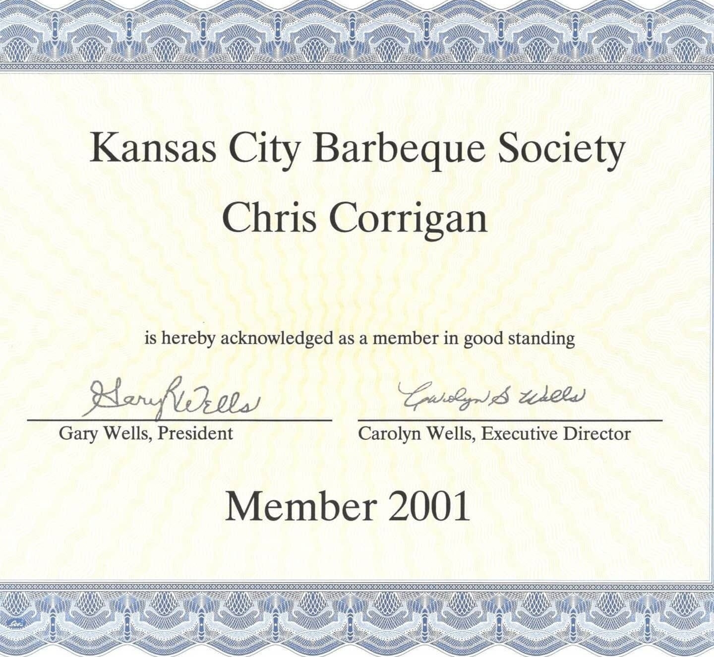 A Kansas City Barbeque Society certificate recognizing Chris Corrigan as a member in good standing in 2001, highlighting his long‑standing involvement in professional barbecue culture.